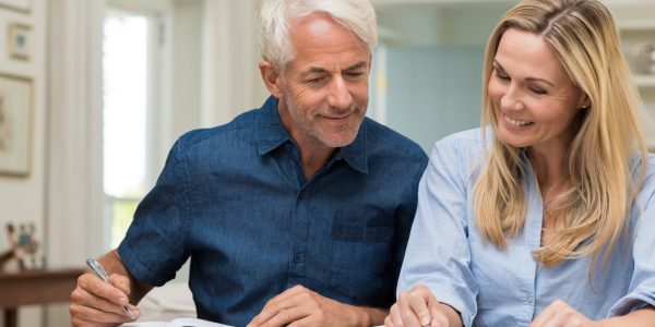 Mature couple doing family finances at home. Senior couple discussing home economics sitting at table. Happy couple sitting at home planning household financials.